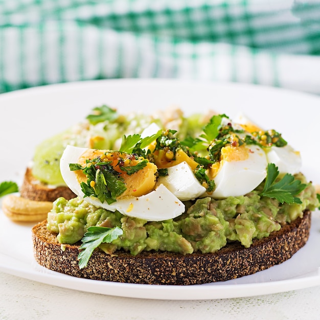 Broodje met avocadopuree, gekookte eieren en boterham roomkaas, kiwi, noten