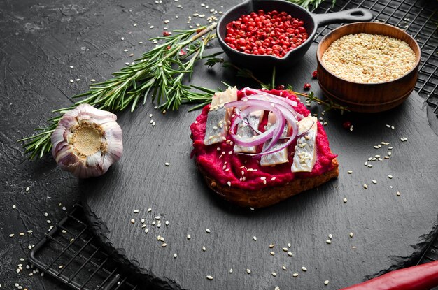 Broodje met bietenhummus haring en uien Ontbijt Op een zwart stenen bord