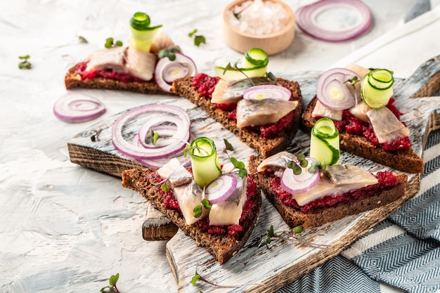 Broodje met stukjes gemarineerde haring met rode ui filet rode biet salade groene komkommer ui en microgreen toast met haring filet scandinavische keuken