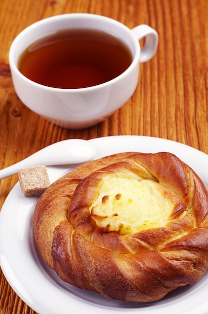 Broodje met vla en kopje thee op houten tafel