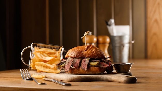 Broodje Pastrami op roggebrood geserveerd met augurk en mosterdsaus Lekkere sandwich met frietaardappelen op donkere achtergrond