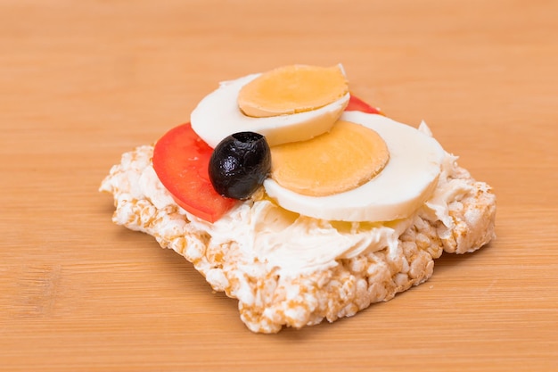 Broodje rijstwafel met tomaten-eieren en olijven