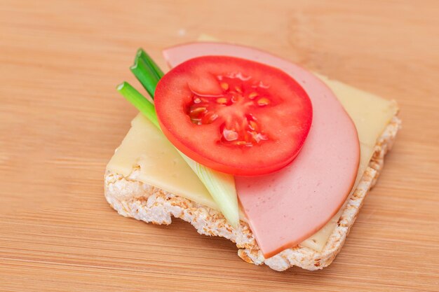 Broodje rijstwafel met tomatenworst, groene uien en kaas