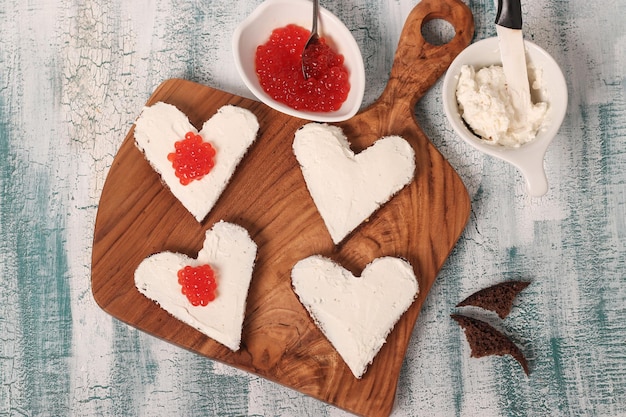 Broodjes koken met rode kaviaar en roomkaas in de vorm van een hart voor Valentijnsdag