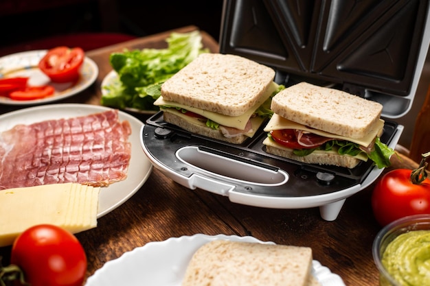 Broodjes koken met verschillende vullingen Tosti-ijzer en verschillende ingrediënten op een houten ondergrond