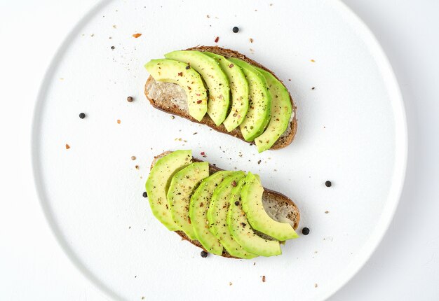 Broodjes met avocado en kruiden op een witte plaat