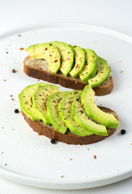 Broodjes met avocado en kruiden op een witte plaat