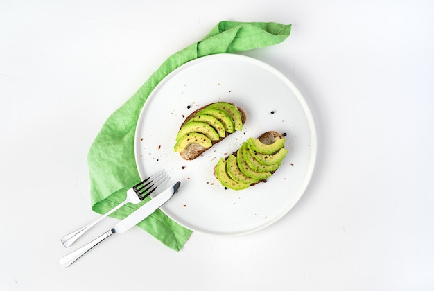 Broodjes met avocado en kruiden op een witte plaat