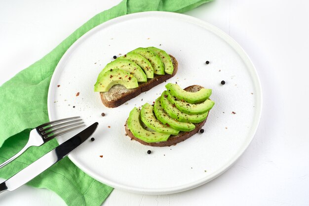 Broodjes met avocado en kruiden op een witte plaat