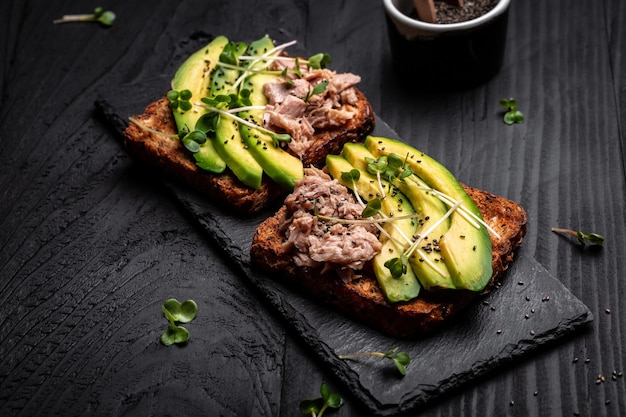 Broodjes met avocado en tonijn op houten snijplank op witte achtergrond bovenaanzicht Gezond ontbijt of snack Voedselrecept achtergrond Close up