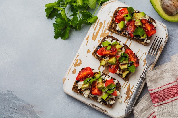 Broodjes met avocado's, cherrytomaatjes en fetakaas met balsamicosaus en koriander. Bovenaanzicht.