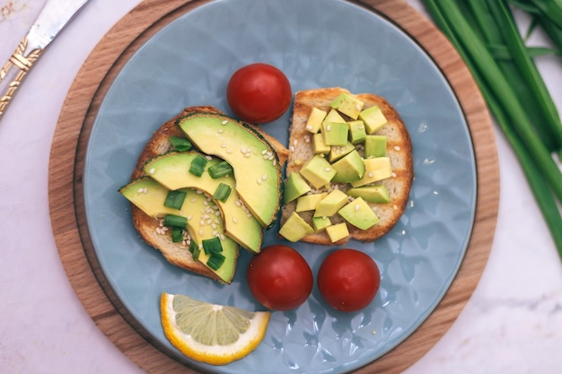 Broodjes met avocado, tomaten en kruiden op een houten achtergrond op tafel. concept van gezond eten en vegetarisme, het juiste ontbijt voor een goede spijsvertering.