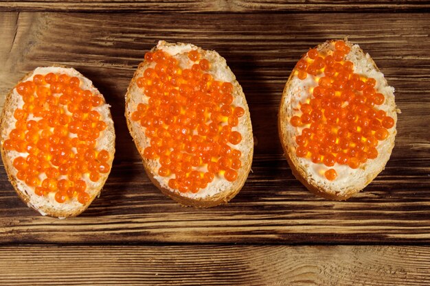 Broodjes met boter en rode kaviaar op houten tafel