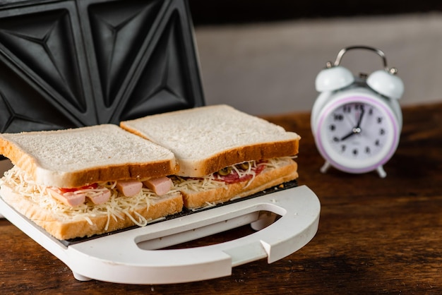 Broodjes met kaasworstolijven koken in een tosti-ijzer op een houten ondergrond