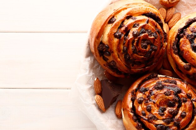 Foto broodjes met kaneel en chocolade op een bruine houten ondergrond. kaneelstokje en zwarte espressokoffie. plaats voor tekst. bovenaanzicht.