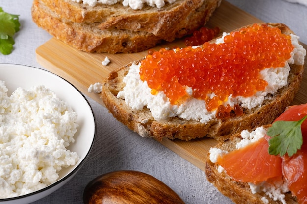 Broodjes met kwark van rode kaviaar en gezouten zalm Houten snijplank Close up