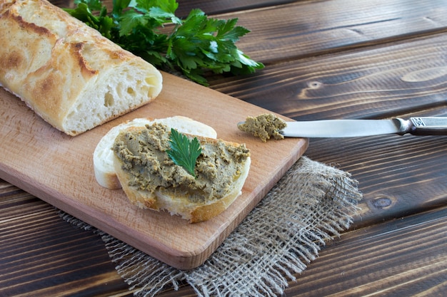 Broodjes met leverpastei en peterselie op de bruine snijplank