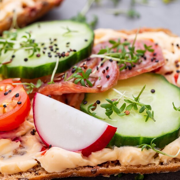 Broodjes met roomkaas, groenten en salami.