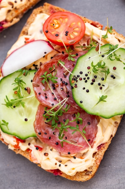 Broodjes met roomkaas, groenten en salami.