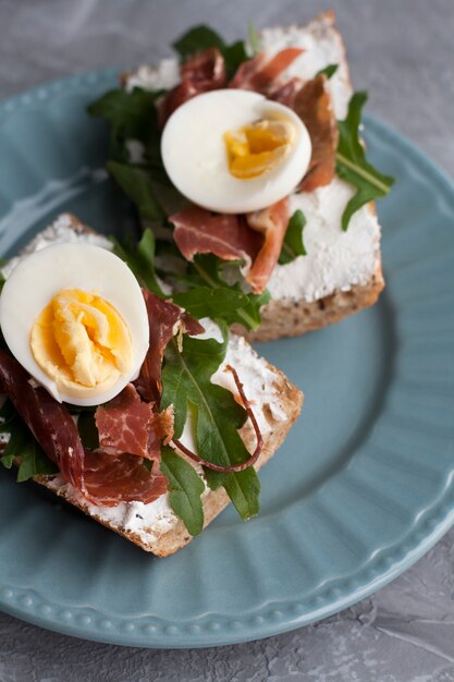 Broodjes met volkoren brood, huisgemaakte kaas, rucola, ham en ei. Gezonde snack.