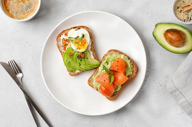 Broodjes op wit bord Twee gezonde toast met avocado zalmeieren Bovenaanzicht Ontbijtconcept