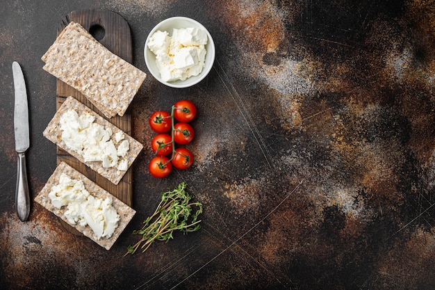 Broodjes wrongel met verse kruiden. Knäckebröd toast met kwark set, op oude donkere rustieke tafel, bovenaanzicht plat lag