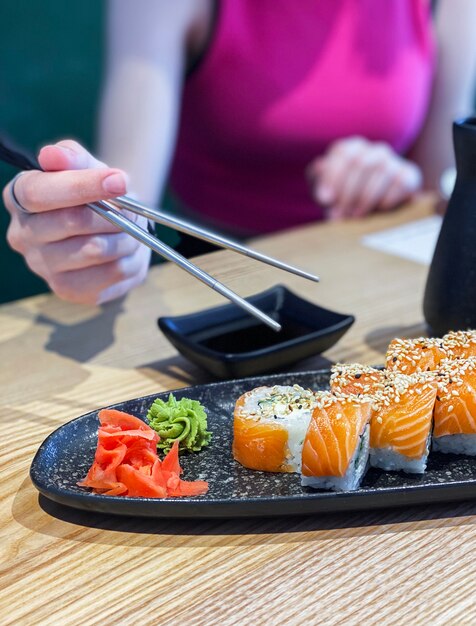 Broodjessushi eten in Japans restaurant, hand met stokjes