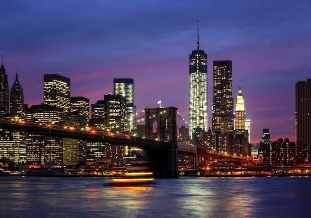 Brooklyn Bridge, East River en Manhattan 's nachts met lichten en reflecties. New York City