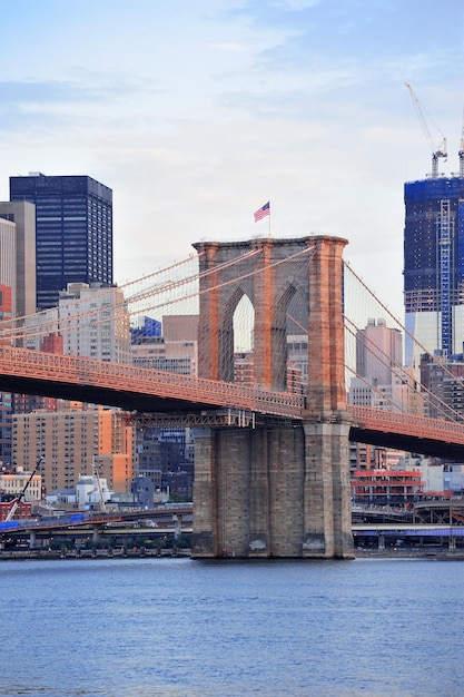 Brooklyn Bridge met lagere skyline van Manhattan in de ochtend met kleurrijke wolk over East River in New York City