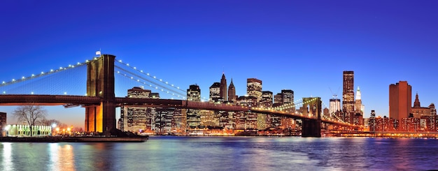 Brooklyn bridge met New York City Manhattan skyline van de binnenstad panorama in de schemering verlicht over East River met blauwe heldere hemel