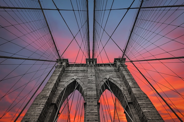 Brooklyn bridge in New York City against dramatic sunset sky with clouds