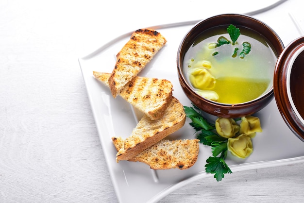 Broth from ravioli and herbs Italian cuisine On a wooden background Top view Free space for your text