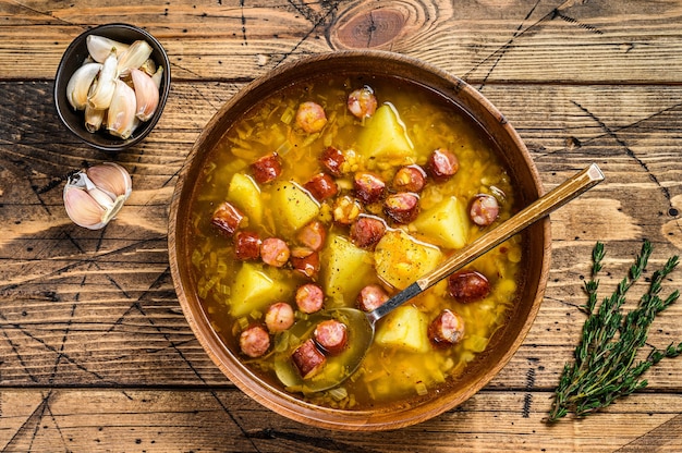 Broth Split pea soup with smoked sausages in a wooden plate