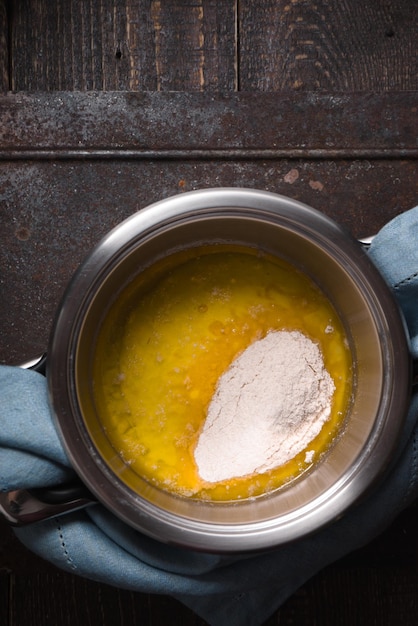 Broth with flour for veloute sauce on wooden table vertical