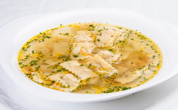 Broth with ravioli on white background