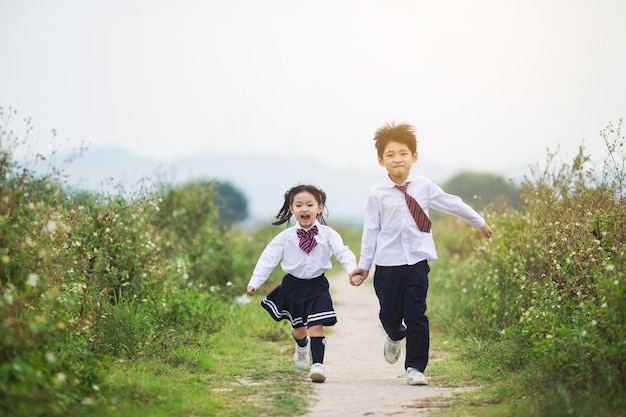 Brother holding sister's hand running in the field