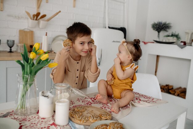 Brother and little sister are hugging in the kitchen Family life at home