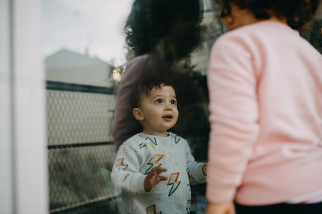 Photo brother looking at sister through window