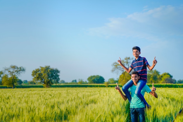 Brother piggyback his little brother in wheat field, rural india