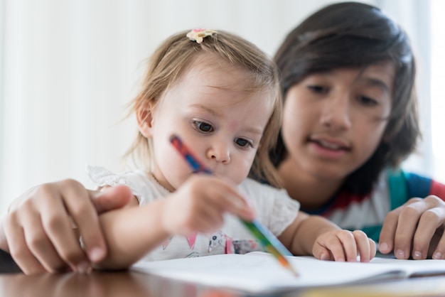 Brother playing and drawing with his baby sister