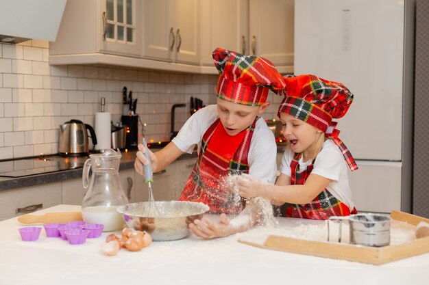 brother and sister are cooking festive dinner cookies in the kitchen new years winter concept