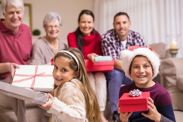 Brother and sister holding gift in front of their family