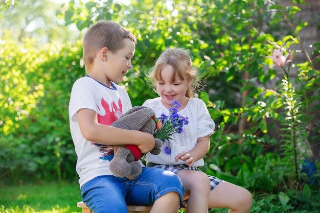 брат и сестра играют в саду с мягкой игрушкой