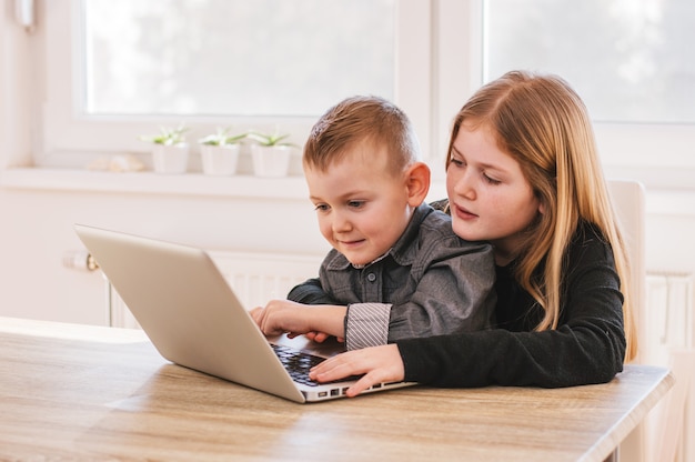 Brother and sister playing games on computer at home