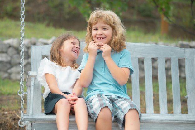Брат и сестра играют на улице, маленький мальчик и девочка работают в саду, два счастливых улыбающихся смеха