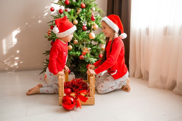 брат и сестра в красных пижамах поздравляют друг друга с Новым годом и Рождеством зимой