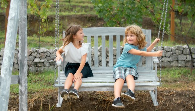 Brother and sister swinging outside little boy and girl working in the garden two happy children in