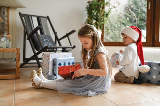 クリスマス プレゼントの包装を解く兄と妹