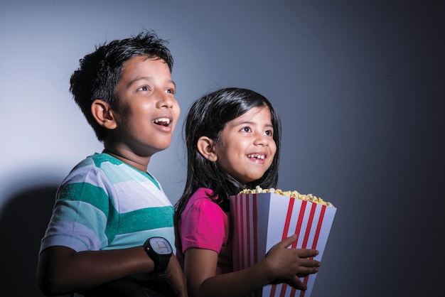 Brother and sister watch a movie in theater and eating snacks with popcorn