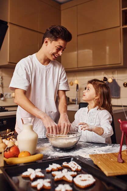 Brother with his little sister preparing food on kitchen and have fun.